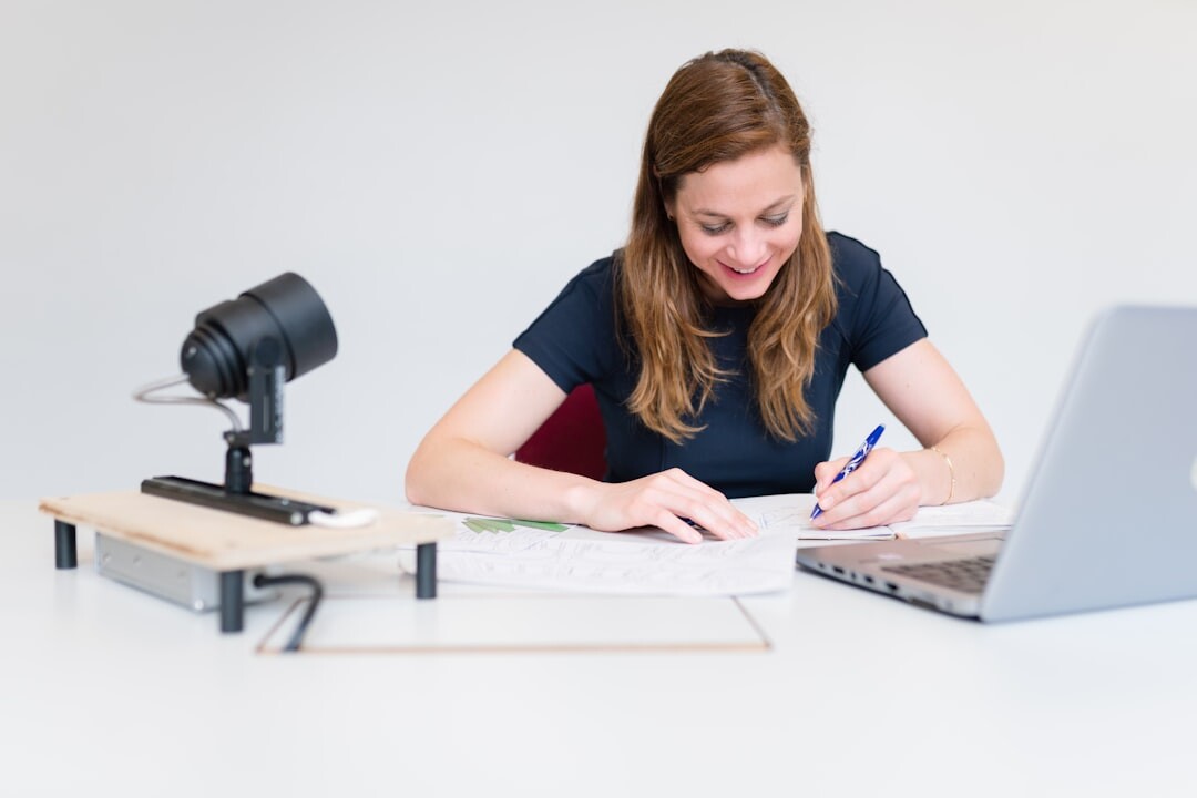 Female journalist working at her desk with a laptop and notebook